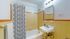 Charming bathroom featuring vintage yellow tiles, a sleek porcelain sink, and a classic bathtub with a pattern shower curtain.