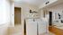 Bright laundry room with modern washer and dryer, accented by sleek shelving for stylish storage. Adjacent cozy living space with contemporary decor.