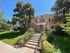 Charming brick apartment building with lush landscaping and inviting entrance, nestled in a peaceful, tree-lined neighborhood.
