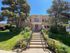 Charming apartment building with classic architecture and lush landscaping, bathed in vibrant sunlight.