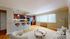 Charming open-plan living room with elegant hardwood floors, featuring a cozy seating area and a modern bar-style kitchen with warm wooden cabinetry.
