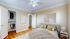 Bright, elegant bedroom with modern decor, featuring a cozy bed, stylish artwork, and a spacious walk-in closet.