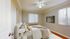 Inviting bedroom with elegant decor, featuring a cozy bed, modern ceiling fan, stylish wall art, and natural light streaming through large windows.