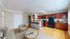 Inviting open-concept living area featuring a cozy sofa, stylish kitchen with elegant wooden cabinets, and a breakfast bar with modern stools.