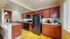 Modern kitchen with rich wooden cabinetry, granite countertops, and sleek black appliances, offering a warm and inviting cooking space.