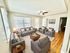 Bright and inviting living room featuring elegant gray sofas, cozy armchairs, wooden floors, and abundant natural light.