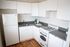 Bright and modern kitchen with sleek white cabinets, stylish gray countertops, and rich hardwood floors.