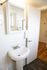 Bright and modern bathroom with sleek pedestal sink, elegant mirror, and contemporary fixtures.
