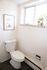 Bright and inviting bathroom featuring a modern toilet, stylish decor, and abundant natural light through a large window with plants.