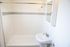 Bright bathroom with modern white tiles, elegant sink, and sleek showerhead.