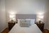Cozy bedroom with elegant decor featuring a plush bed, stylish pillows, and warm bedside lighting.