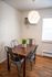 Cozy dining nook featuring a wooden table for four, metal chairs, and a modern geometric pendant light, perfect for intimate meals.