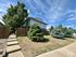 Charming suburban home with lush greenery and a clear blue sky, offering tranquil living in a picturesque neighborhood.