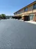Bright and inviting apartment complex featuring spacious parking area and private outdoor seating, perfect for a sunlit relaxation spot.
