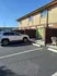 Inviting suburban apartment with convenient parking, featuring a modern vehicle in front of charming two-story brick and wood exterior.
