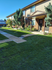 Charming townhouse exterior with lush green lawns, pathway, and welcoming porch, perfect for comfortable living.