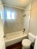 Modern bathroom with marble tiles, bathtub, and frosted window