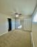 Bright spacious bedroom with plush carpeting and a ceiling fan, featuring ample closet space and natural light from the window.