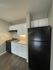 Compact kitchen with black appliances, white cabinets, and elegant countertops in a cozy apartment setting.