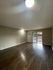 Bright and spacious living room with wooden floors and large window offering ample natural light.