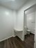 Bright corner with dark wood flooring leading into a bathroom, featuring a built-in shelf.