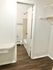 Stylish apartment hallway with sleek wooden floors leading to a modern bathroom.