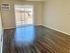 Spacious living room with wooden flooring, large window blinds, and an air conditioning unit.