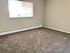 Spacious carpeted bedroom with large window and natural light.
