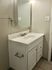 Elegant bathroom vanity with a white counter and storage cabinets, enhanced by soft lighting.