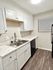 Contemporary kitchen with white cabinetry, marble countertops, and stainless steel sink.