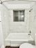 Bright bathroom with white marble tiles and a sleek bathtub.