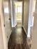 Bright hallway with modern wood flooring and doors leading to a bathroom and other rooms.