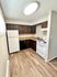 Modern kitchen with sleek wooden cabinets, light wood flooring, and essential appliances.
