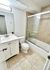 Contemporary bathroom with sleek vanity, tiled walls, and a glass-enclosed bathtub.