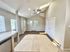 Open-concept living space with tiled flooring, large windows, and ceiling fan, offering ample natural light.