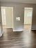 Spacious room with elegant hardwood flooring and two bright doorways.