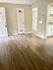 Spacious room with elegant hardwood flooring and modern kitchen view.
