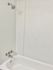 Pristine white bathtub with chrome fixtures and a modern showerhead.