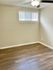 Spacious bedroom with hardwood floors and ample natural light from a large window.