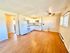 Bright open kitchen and living area with hardwood floors and ceiling fan.