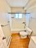 Bright bathroom featuring a white bathtub, modern toilet, tiled walls, and wooden flooring.
