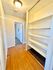 Well-lit hallway featuring built-in shelving and wood flooring, leading to a carpeted room.
