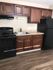 Sleek kitchen with dark wooden cabinets, black appliances, and a cozy layout, ideal for culinary enthusiasts.