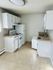 Compact white kitchen with modern appliances and ample counter space.