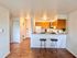 Contemporary apartment kitchen with wooden cabinets, breakfast bar, and elegant wooden flooring.