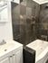 Contemporary bathroom with sophisticated dark stone tiles and a classic white bathtub.