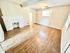 Bright living room with wooden flooring, a white brick fireplace, and ceiling fan enhancing comfort.