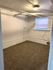 Inviting basement room with soft carpeting, a light fixture, and a small window.