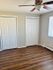 Spacious bedroom with laminate wood flooring, double closets, and a ceiling fan.