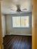 Inviting bedroom with wood flooring, ceiling fan, and large window with blinds.